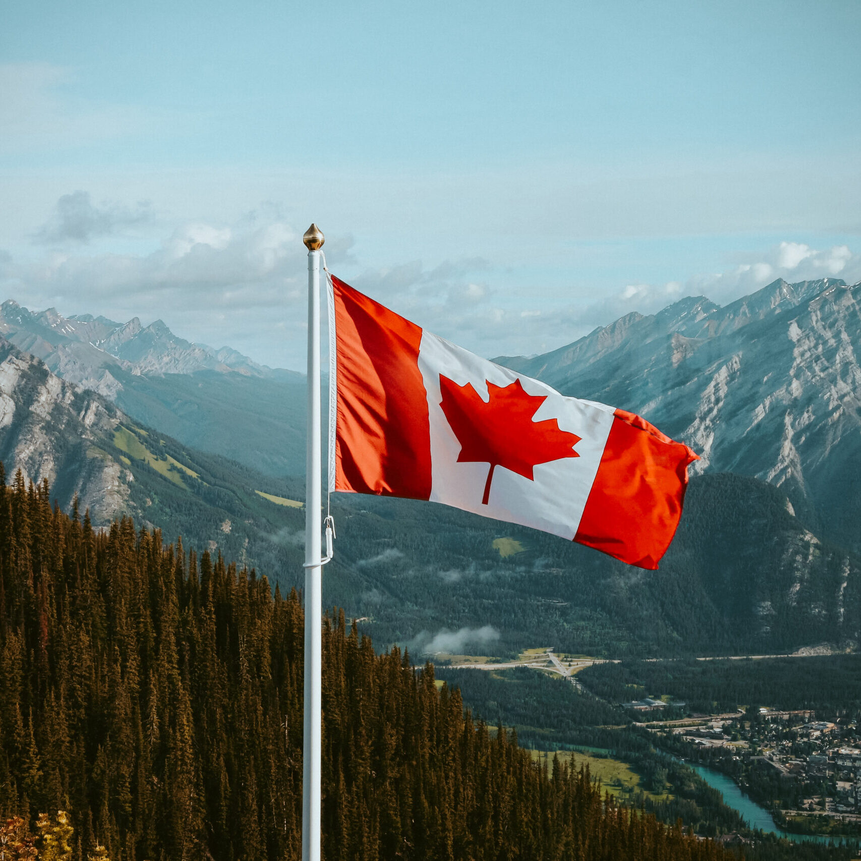 Canadian flag with mountain and small town views in summer